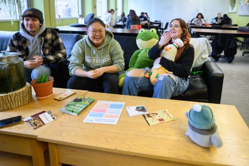 students sitting on a couch with environmental mascot plushies