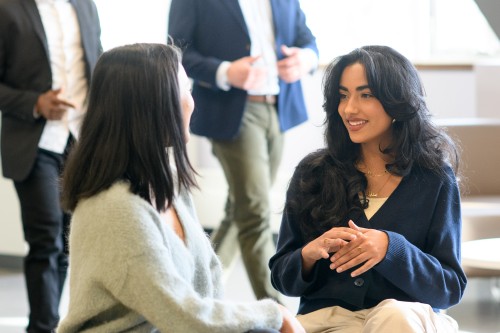 two students at a table talking and smiling 
