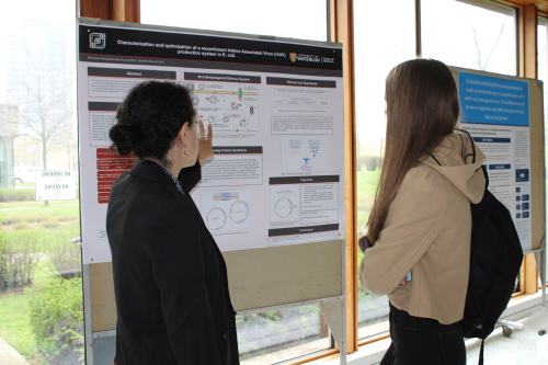 a woman pointing at a scientific poster in discussion with another woman