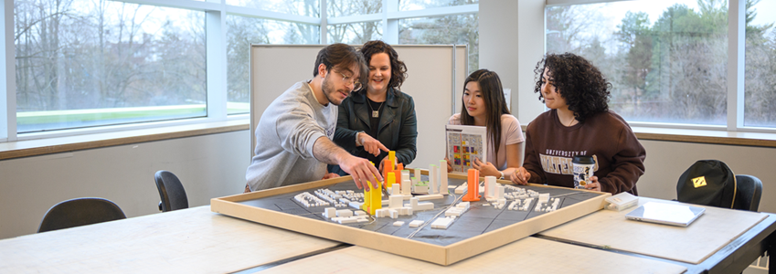 Students lookign at an architectural model on a desk
