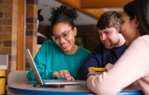 Two female students and a male student looking at a laptop