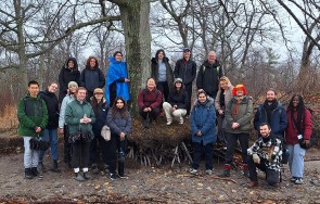 A number of students and instructors standing in front of a large tree in the forest