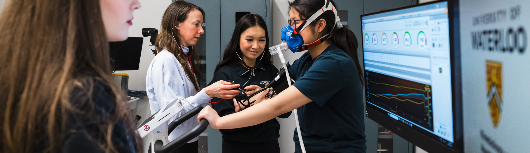 A woman undergoing a respiratory test while a doctor and assistants look at the results