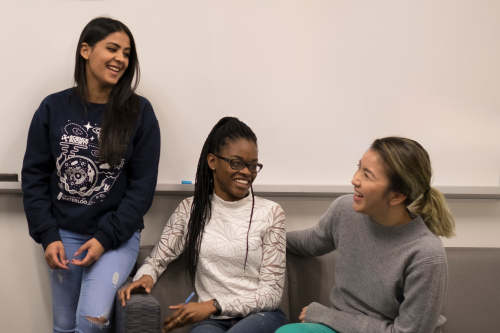 Three students sitting on a couch laughing