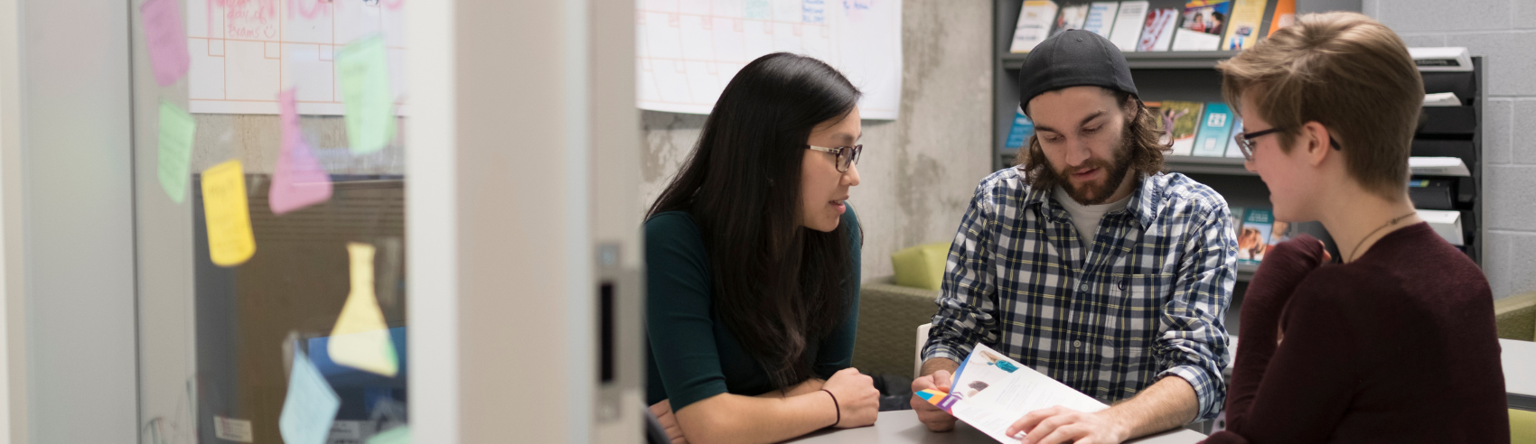 Three students looking at science papers at a table
