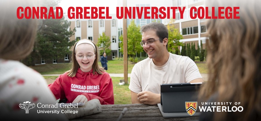 Students of Conrad Grebel studying at a table with the text 'Conrad Grebel University College' on it